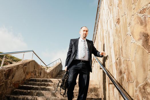 Business executive with briefcase going down the stairs.