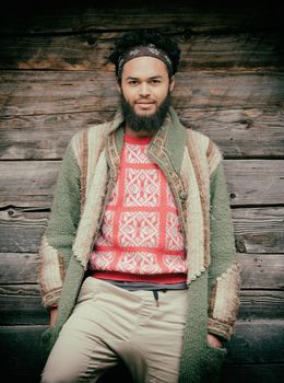 portrait of young hipster,  man with beard in front of old vintage wooden house