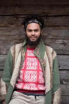 portrait of young hipster,  man with beard in front of old vintage wooden house