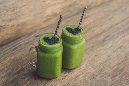 Fresh green smoothie with banana and spinach with heart of sesame seeds. Love for a healthy raw food concept.