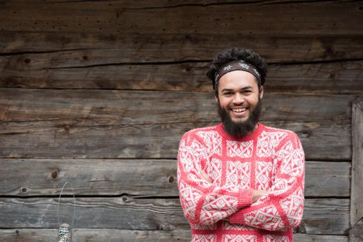 portrait of young hipster,  man with beard in front of old vintage wooden house