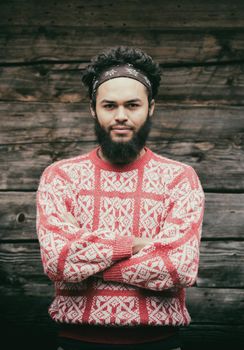 portrait of young hipster,  man with beard in front of old vintage wooden house