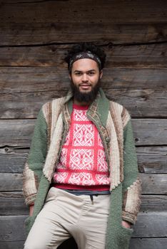 portrait of young hipster,  man with beard in front of old vintage wooden house