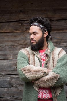 portrait of young hipster,  man with beard in front of old vintage wooden house