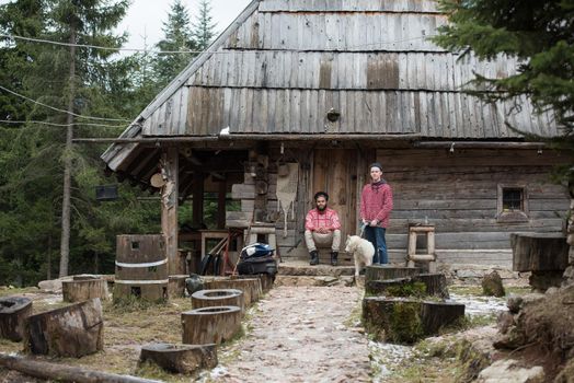 hipsters couple portrait, two young  man with white husky dog  sitting in front of old wooden retro house