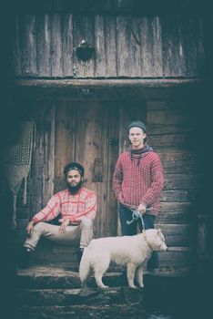 hipsters couple portrait, two young  man with white husky dog  sitting in front of old wooden retro house