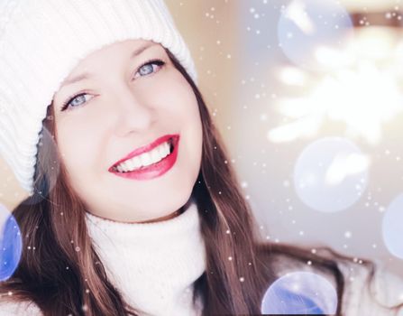 Christmas, people and winter holiday concept. Happy smiling woman wearing white knitted hat as closeup face xmas portrait, snow glitter and bokeh effect.