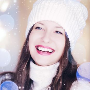 Christmas, people and winter holiday concept. Happy smiling woman wearing white knitted hat as closeup face xmas portrait, snow glitter and bokeh effect.