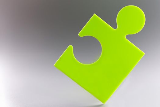 Closeup of green puzzle piece on gray background. Business strategies concept