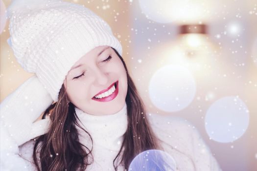 Christmas, people and winter holiday concept. Happy smiling woman wearing white knitted hat as closeup face xmas portrait, snow glitter and bokeh effect.