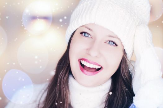 Christmas, people and winter holiday concept. Happy smiling woman wearing white knitted hat as closeup face xmas portrait, snow glitter and bokeh effect.