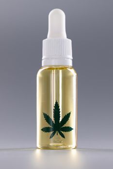 Closeup of bottle of marijuana oil on gray background. Hemp cosmetics concept