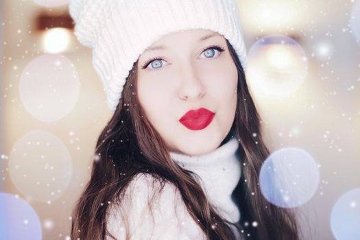 Christmas, people and winter holiday concept. Beautiful woman wearing red lipstick makeup sending a kiss, closeup face xmas portrait, snow glitter and bokeh effect.