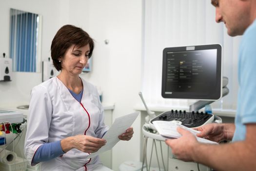 Doctor cardiologist in the office of ultrasound diagnostics with the patient examines medical tests during a health check-up in a modern clinic. Medical consultation. healthcare, medical service.