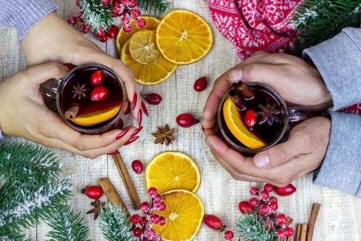 Hot mulled wine in female hands, spices on weathered wooden table. Sweet-home concept