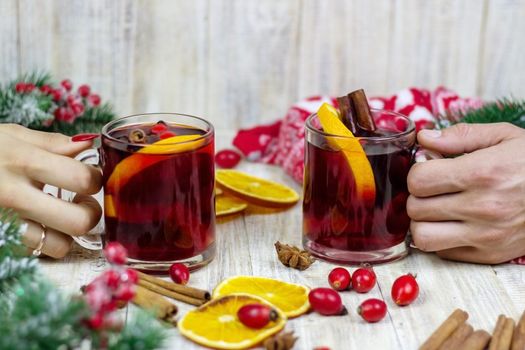 Hot mulled wine in female hands, spices on weathered wooden table. Sweet-home concept