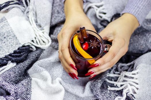 Hot mulled wine in male and female hands, spices. Sweet home concept
