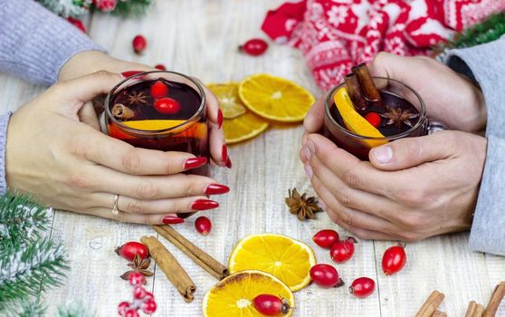 Hot mulled wine in female hands, spices on weathered wooden table. Sweet-home concept
