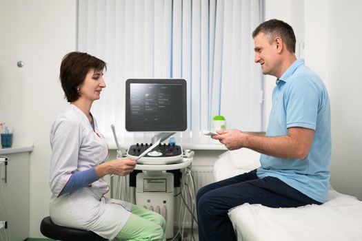 Doctor cardiologist in the office of ultrasound diagnostics with the patient examines medical tests during a health check-up in a modern clinic. Medical consultation. healthcare, medical service.