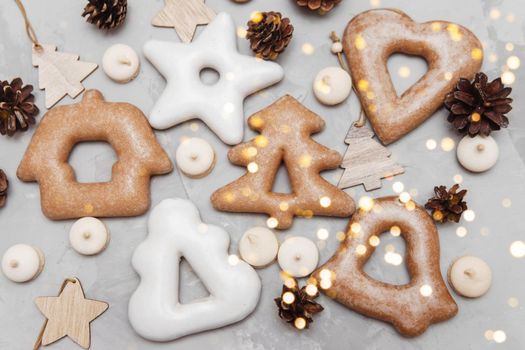 Banner for Christmas and New Year gingerbread stars, houses, Christmas trees, toys on a gray concrete background, Christmas lights bokeh in the foreground.