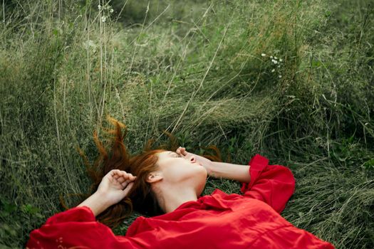 woman in red dress lies on the grass charm freedom. High quality photo