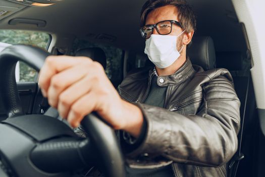 Young man driving car in medical mask, portrait