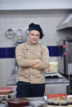 Closeup of a concentrated male pastry chef decorating dessert cake food in the kitchen