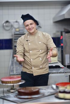 Closeup of a concentrated male pastry chef decorating dessert cake food in the kitchen