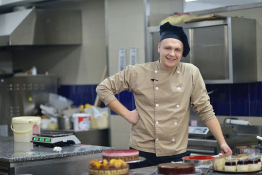 Closeup of a concentrated male pastry chef decorating dessert cake food in the kitchen