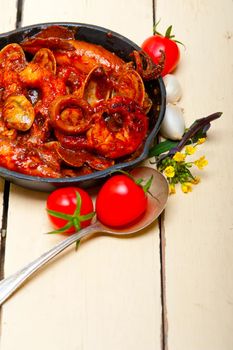 fresh seafood stew prepared on an iron skillet ove white rustic wood table 