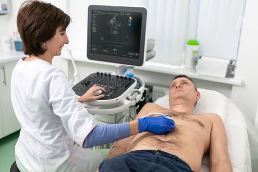 Doctor using ultrasound machine to scan heart of a male patient. Cardiologist makes a patient an echocardiographic test in a clinic. Patient under ultrasound examination in the hospital. Cardiovascular tests.