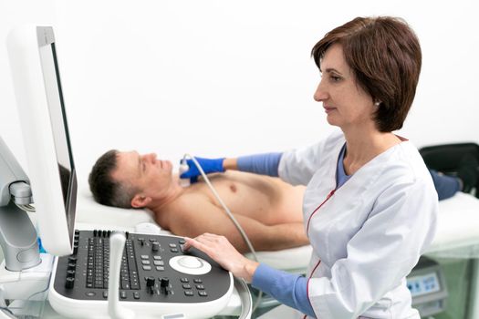 Doctor doing a doppler sonography a male patient in a cardiology clinic. Cardiologist performing an ultrasound examination at the cardiovascular hospital. Echocardiography procedure.