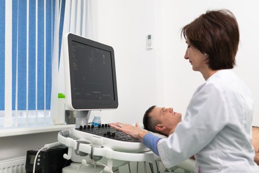 Doctor doing a doppler sonography a male patient in a cardiology clinic. Cardiologist performing an ultrasound examination at the cardiovascular hospital. Echocardiography procedure.