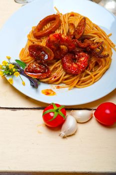 Italian seafood spaghetti pasta on red tomato sauce over white rustic wood table