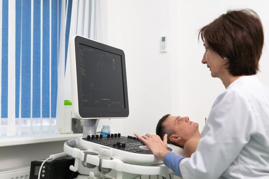 Doctor using ultrasound machine to scan heart of a male patient. Cardiologist makes a patient an echocardiographic test in a clinic. Patient under ultrasound examination in the hospital. Cardiovascular tests.