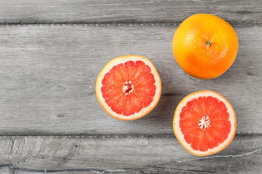 Table top view on red grapefruits, on cut in half, placed on gray wood desk.