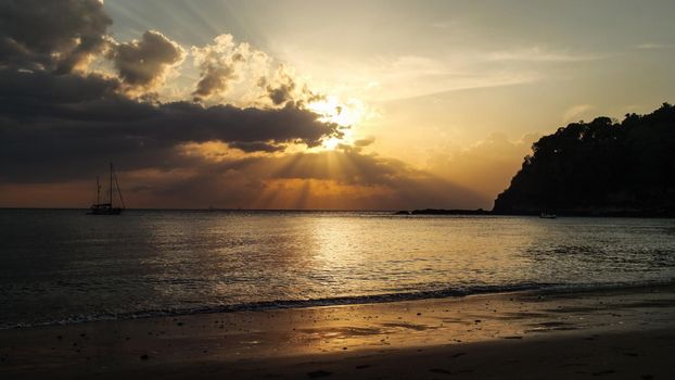 Tranquil beach with silhouette of ship on the sea in background, during golden sunset light. Kantiang Bay, Koh Lanta, Thailand