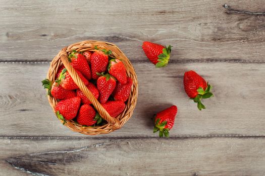 Table top view on small basket full of strawberries on wooden desk.