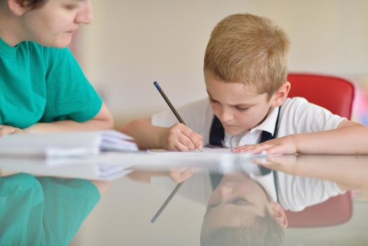 young mom woman doing home work with elementary school grade boy at home in kitchen