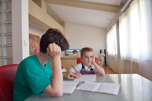 young mom woman doing home work with elementary school grade boy at home in kitchen