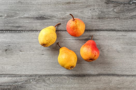 Table top view on four ripe pears on gray wood desk.