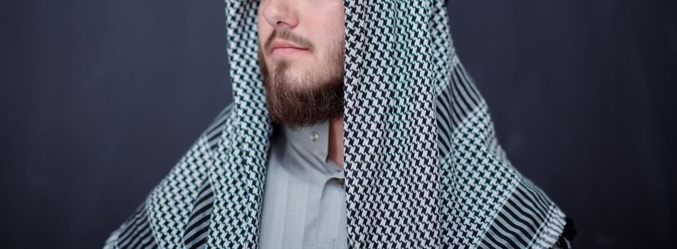 portrait of young arabian man in traditional clothes in front of black chalkboard representing modern islam fashion and ramadan kareem concept