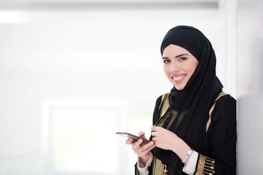 young modern muslim business woman using smartphone wearing traditional hijab clothes at home