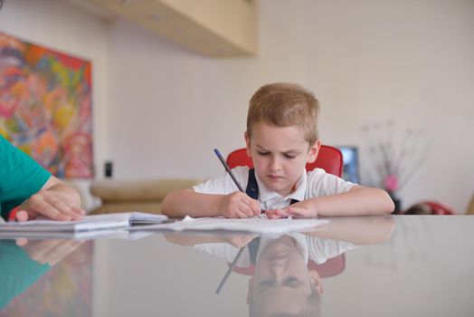 young mom woman doing home work with elementary school grade boy at home in kitchen