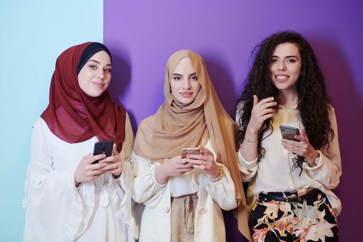 group portrait of beautiful muslim women two of them in fashionable dress with hijab isolated on colorful background representing modern islam fashion and ramadan kareem concept