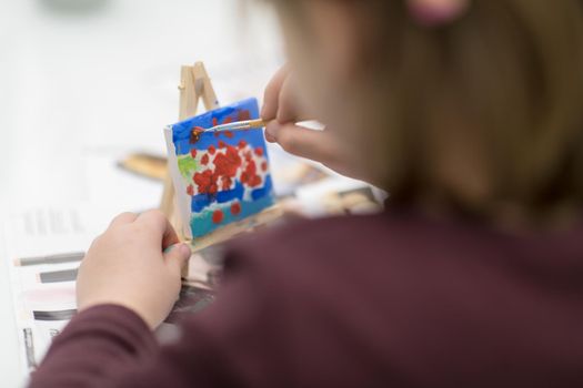 happy little girl painting on canvas image at home