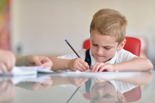 young mom woman doing home work with elementary school grade boy at home in kitchen