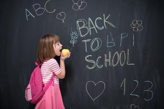 happy child with apple and back to school drawing in background on black chalkboard