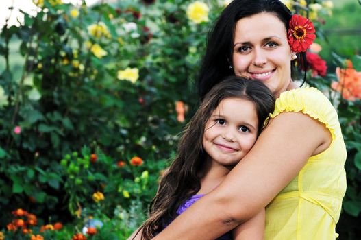 beautiful mom and daughter outdoor in garden  together with flower have fun and hug 