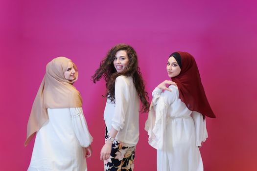 group portrait of beautiful muslim women two of them in fashionable dress with hijab isolated on pink background representing modern islam fashion and ramadan kareem concept